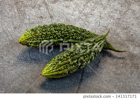 Two fresh green bitter melons on textured gray surface Two fresh green bitter melons on textured gray surface 141317171