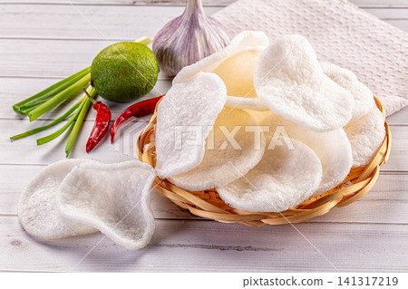 Crispy fried pork rinds in woven basket with lime garlic chili and green onions on rustic wood Crispy fried pork rinds in woven basket with lime garlic chili and green onions on rustic wood 141317219