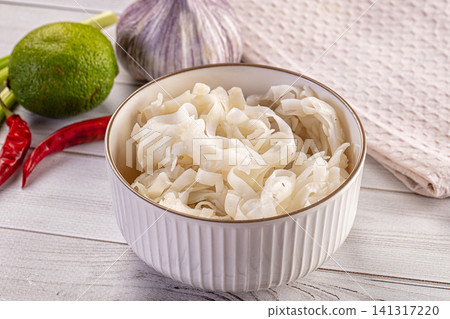 White rice noodles in ceramic bowl with lime garlic and red chili on wooden table White rice noodles in ceramic bowl with lime garlic and red chili on wooden table 141317220