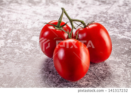 Three ripe red tomatoes on vine against textured gray background Three ripe red tomatoes on vine against textured gray background 141317232