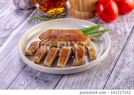 Crispy roasted duck breast sliced on white plate with green onions Crispy roasted duck breast sliced on white plate with green onions 141317242