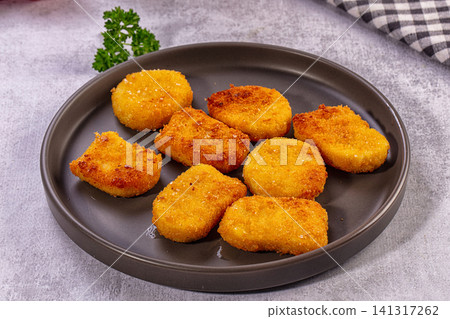 Crispy golden fried nuggets on dark plate with parsley garnish Crispy golden fried nuggets on dark plate with parsley garnish 141317262