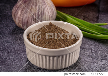 Ground black pepper in ceramic bowl with garlic and green onions on dark surface Ground black pepper in ceramic bowl with garlic and green onions on dark surface 141317278