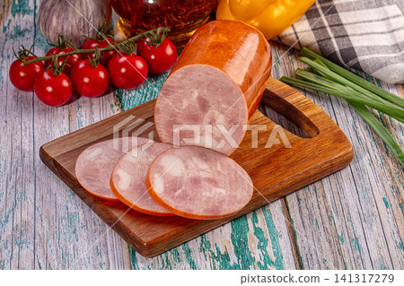 Sliced smoked sausage on wooden cutting board with fresh vegetables Sliced smoked sausage on wooden cutting board with fresh vegetables 141317279