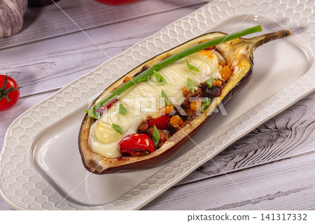 Stuffed eggplant with melted cheese and vegetables on white plate Stuffed eggplant with melted cheese and vegetables on white plate 141317332