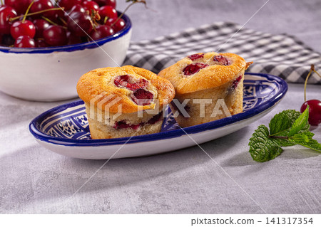 Cherry muffins on blue patterned plate with fresh cherries and mint 141317354