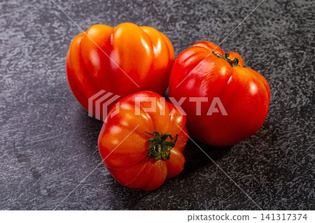 Three ripe red tomatoes on dark textured surface Three ripe red tomatoes on dark textured surface 141317374