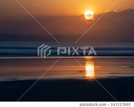 Golden hour sunset at Triangulasi Beach, Alas Purwo National Park, East Java, Indonesia. Scenic tropical coastal landscape with dramatic sky and reflection on wet sand. 141317693