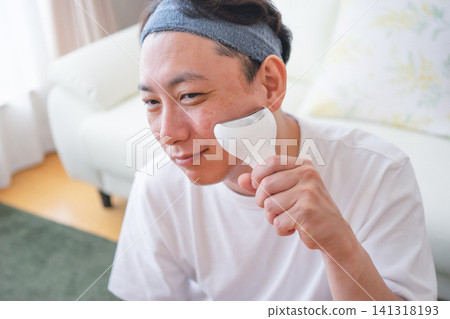 40多歲的男性在家中使用臉部美容儀進行美容護理。 141318193