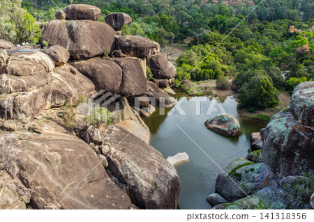 Aerial view of the natural rock pool, elevated viewing platform and striking granite rock formations at Cranky Rock Nature Reserve near Warialda, NSW. Carved by Reedy Creek Aerial view of the natural rock pool, elevated viewing platform and striking granite rock formations at Cranky Rock Nature Reserve near Warialda, NSW. Carved by Reedy Creek 141318356