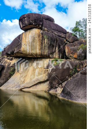 Scenic view of the natural rock pool and impressive granite rock formations at Cranky Rock Nature Reserve near Warialda, NSW. Set beneath a cloudy blue sky and surrounded by native bushland Scenic view of the natural rock pool and impressive granite rock formations at Cranky Rock Nature Reserve near Warialda, NSW. Set beneath a cloudy blue sky and surrounded by native bushland 141318358