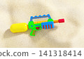 Colorful plastic water gun toy on a sandy beach 141318414