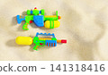 Two bright toy water blasters on beach sand with copy space. Summer fun and family holiday concept 141318416