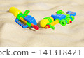 Two colorful plastic water guns lying on sandy beach dunes. Summer activity and kids holiday concept 141318421