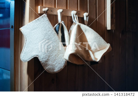 Various sauna accessories in a wooden sauna. Sauna glove and hats on a wooden hanger. Various sauna accessories in a wooden sauna. Sauna glove and hats on a wooden hanger. 141318472