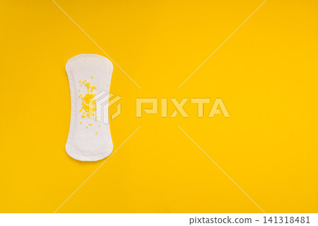 Sanitary Pad with Yellow Beads Symbolizing Urinary Leakage on Yellow Background Sanitary Pad with Yellow Beads Symbolizing Urinary Leakage on Yellow Background 141318481