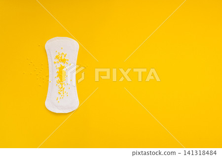 Sanitary Pad with Yellow Beads Symbolizing Urinary Leakage on Yellow Background Sanitary Pad with Yellow Beads Symbolizing Urinary Leakage on Yellow Background 141318484