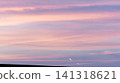 A minimalist landscape of pale pink and blue clouds and contrails adorning the sunset sky. 141318621