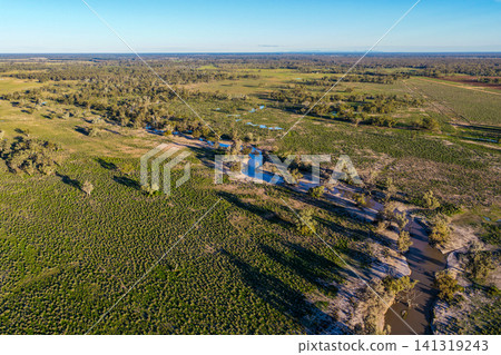 Aerial view of a creek winding through the lush green landscape surrounding the Pilliga Artesian Bore Baths, highlighting the natural beauty and peaceful bushland setting near Pilliga, NSW, Australia Aerial view of a creek winding through the lush green landscape surrounding the Pilliga Artesian Bore Baths, highlighting the natural beauty and peaceful bushland setting near Pilliga, NSW, Australia 141319243