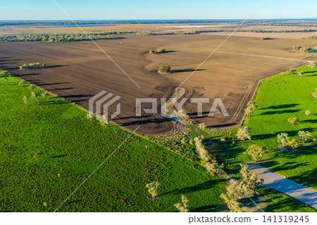 Aerial view showcasing cultivated farmland surrounded by the lush green landscape of Pilliga, highlighting striking natural patterns, rich textures and the vibrant colours of the rural countryside Aerial view showcasing cultivated farmland surrounded by the lush green landscape of Pilliga, highlighting striking natural patterns, rich textures and the vibrant colours of the rural countryside 141319245