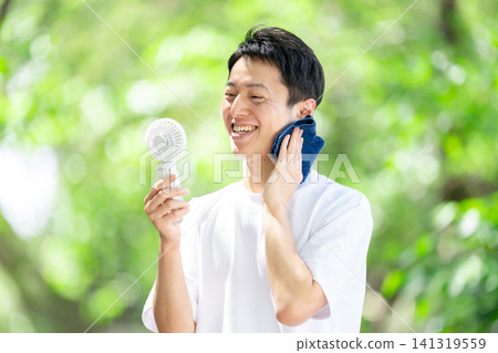 酷暑中，一名男子拿著便攜式風扇。 141319559