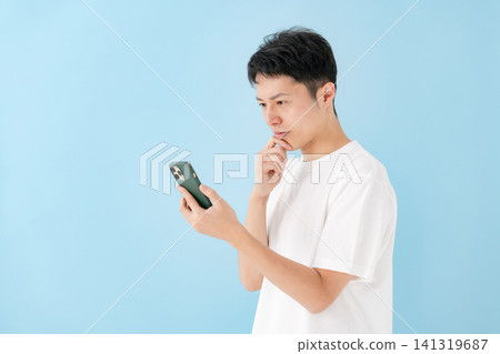 A man intently looking at his smartphone A man intently looking at his smartphone 141319687