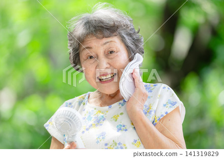 Senior woman, electric fan, fresh green leaves Senior woman, electric fan, fresh green leaves 141319829