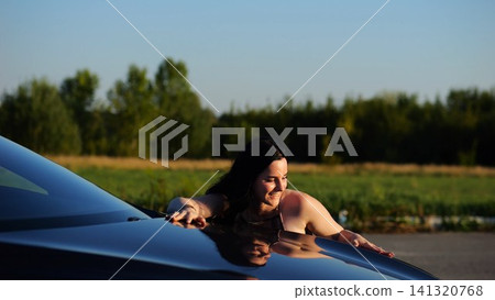 Beautiful smiling girl bought new electrical vehicle and hugging hood auto. Happy young woman enjoying modern electric automobile. Concept of buy or rent car. Slow motion Beautiful smiling girl bought new electrical vehicle and hugging hood auto. Happy young woman enjoying modern electric automobile. Concept of buy or rent car. Slow motion 141320768