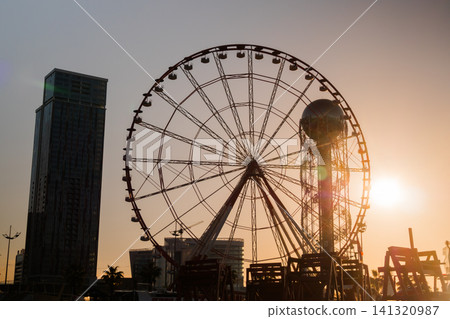 View of silhouette of ferris wheel and alphabet tower against the sunset sky View of silhouette of ferris wheel and alphabet tower against the sunset sky 141320987
