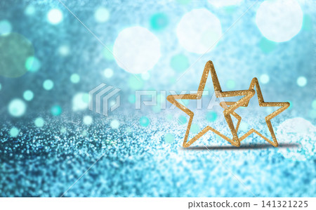 Close up photo of two golden star shaped outlines placed on a sparkling blue surface with bokeh light effects. 141321225