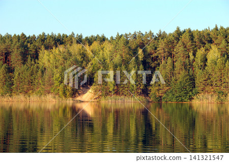 Beautiful river landscape with green forest reflected in the calm water surface. Beautiful river landscape with green forest reflected in the calm water surface. 141321547