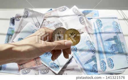 Two Bitcoin coins against a backdrop of Russian rubles Two Bitcoin coins against a backdrop of Russian rubles 141321576