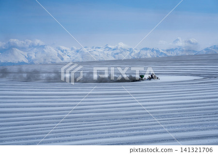 北海道美瑛的農民在白雪皚皚的田野上撒融雪劑;十勝山脈和田野迎接春天。 北海道美瑛的農民在白雪皚皚的田野上撒融雪劑;十勝山脈和田野迎接春天。 141321706