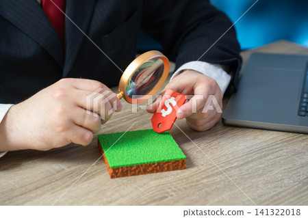 A businessman researches the price of a plot of land. Land valuation concept. Property cost analysis, real estate investment, land appraisal, market research and financial planning. A businessman researches the price of a plot of land. Land valuation concept. Property cost analysis, real estate investment, land appraisal, market research and financial planning. 141322018