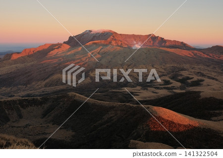Mount Aso's Takadake peak, bathed in the red glow of the setting sun, and the Venus Belt appearing on the eastern horizon. 141322504