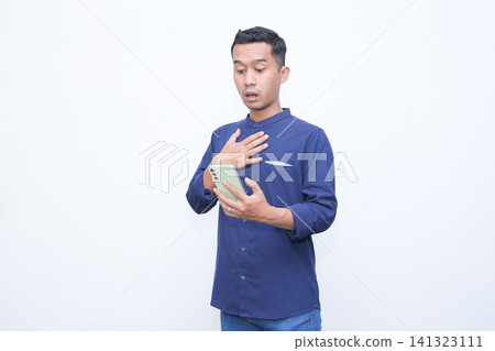 Man holds phone, hand covers mouth in shock. His eyes widen, eyebrows raised. White background isolates the emotion clearly. Ideal for stories of surprise or unexpected news. Man holds phone, hand covers mouth in shock. His eyes widen, eyebrows raised. White background isolates the emotion clearly. Ideal for stories of surprise or unexpected news. 141323111