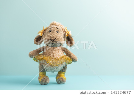 Knitted sheep ballerina toy standing on blue background 141324677