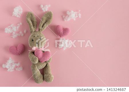 Stuffed bunny holding heart on pink background Stuffed bunny holding heart on pink background 141324687