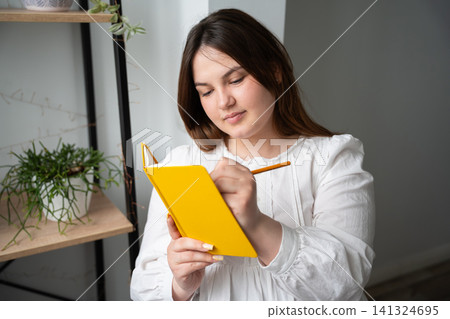 Young woman engaged in journaling and self-development at home. Education study planning personal growth and mindfulness Young woman engaged in journaling and self-development at home. Education study planning personal growth and mindfulness 141324695