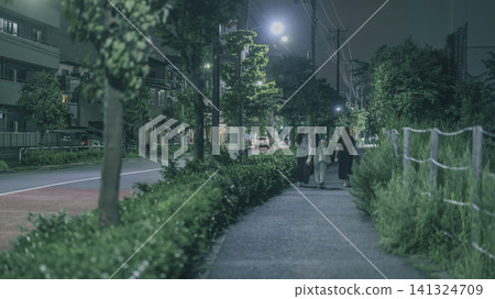 The backs of people walking home at night The backs of people walking home at night 141324709