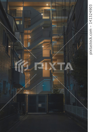 A dark alleyway, illuminated by the lights of an apartment building. A dark alleyway, illuminated by the lights of an apartment building. 141324903