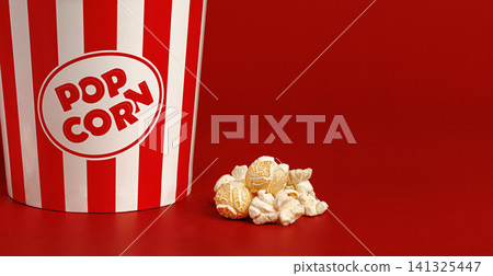 Close up of popcorn kernels on red background with copy space. Cinema advertising template. Close up of popcorn kernels on red background with copy space. Cinema advertising template. 141325447