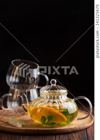 Herbal tea with orange and mint in glass teapot Herbal tea with orange and mint in glass teapot 141325678
