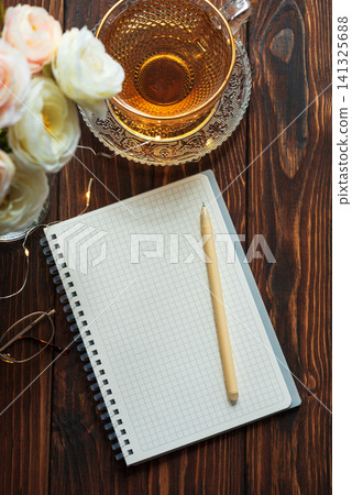 Morning routine with notebook, tea and flowers on wooden table Morning routine with notebook, tea and flowers on wooden table 141325688