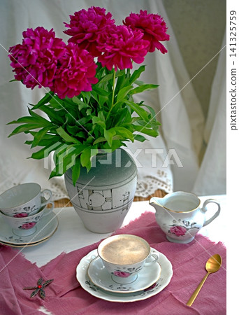 A bouquet of burgundy peonies, a coffee cup, and a porcelain set. A bouquet of burgundy peonies, a coffee cup, and a porcelain set. 141325759