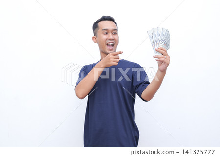Man beams joyfully, flexing arm proudly. He holds money in one hand, smiling widely. Studio lighting highlights his enthusiastic expression. Perfect for business, finance, or success-themed projects Man beams joyfully, flexing arm proudly. He holds money in one hand, smiling widely. Studio lighting highlights his enthusiastic expression. Perfect for business, finance, or success-themed projects 141325777