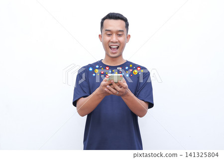 Young man smiles while using smartphone. Colorful emojis float above his head. He enjoys social media interaction. Image captures joyful digital engagement. Perfect for digital marketing visuals Young man smiles while using smartphone. Colorful emojis float above his head. He enjoys social media interaction. Image captures joyful digital engagement. Perfect for digital marketing visuals 141325804