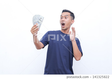 Man holds money, eyes wide, mouth open in surprise. He gestures with free hand, showing excitement. Pure white background emphasizes his reaction. Ideal for finance, unexpected gains, or lucky moments Man holds money, eyes wide, mouth open in surprise. He gestures with free hand, showing excitement. Pure white background emphasizes his reaction. Ideal for finance, unexpected gains, or lucky moments 141325822