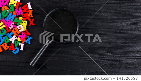 colored letters of the alphabet with a magnifying glass on a black background 141326558