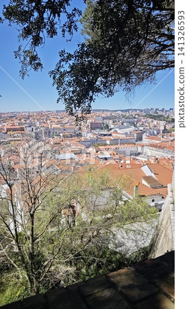 Panoramic view of Lisbon cityscape featuring terracotta rooftops, urban buildings, and greenery, with a clear blue sky above and distant hills in the background Panoramic view of Lisbon cityscape featuring terracotta rooftops, urban buildings, and greenery, with a clear blue sky above and distant hills in the background 141326593
